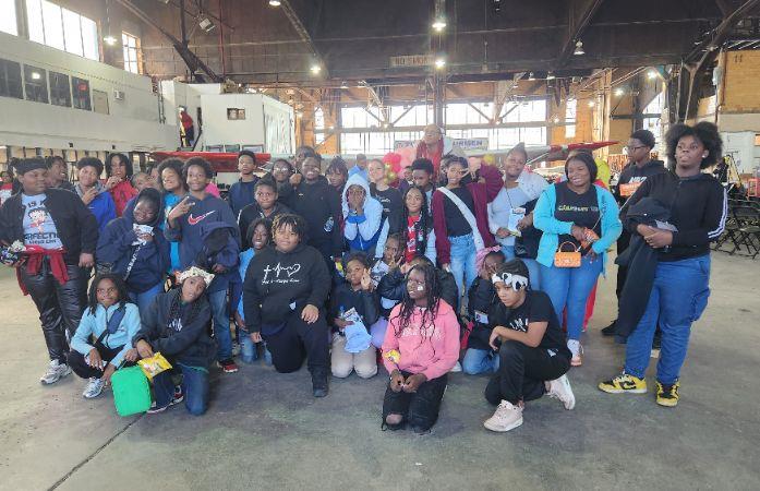  Group of students posing for picture at airport, airport hangar.